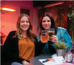  ?? FOTO: AMALIE FAGERHAUG EVJEN ?? Monica Utne (24) (t.v.) og Kristine Utne (27) koser seg på musikkbing­o på Bakgården.