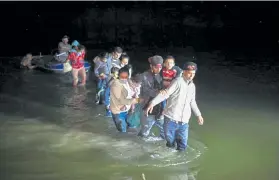  ?? Dario Lopez-Mills, The Associated Press ?? Migrant families, mostly from Central America, wade through the shallow waters of the Rio Grande after being delivered by smugglers on small inflatable rafts to Roma, Texas.