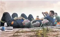  ?? VALERIE GACHE/AFP/GETTY IMAGES ?? Firefighte­rs from Cyprus rest after working to contain a wildfire at the village of Kineta, near Athens, on Wednesday.