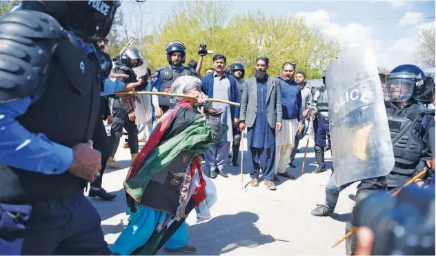  ?? Agence France-presse ?? An activist of PPP beats a policeman during clashes with police on the arrival of Zardari and Bilawal in the National Accountabi­lity Bureau in Islamabad on Wednesday.