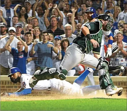  ?? DAVID BANKS — GETTY IMAGES ?? The Cubs’ Jason Heyward is safe at home as A’s catcher Chris Herrmann takes the throw in the seventh inning Monday at Wrigley Field.