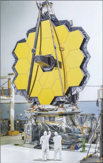  ?? CHRIS GUNN / NASA ?? Workers look at the primary mirror of the James Webb Space Telescope in 2016 at Goddard Space Flight Center in Greenbelt, Md. Once the telescope is launched, it will unfold in a series of movements that ends with the 18 gold-plated hexagons of the mirror snapped into place.