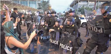  ?? ROB SCHUMACHER/THE REPUBLIC ?? With megaphone in hand, Reshauna Striggles kneels with three Phoenix police officers before a line of other officers Monday night.