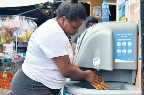  ?? KENYON HEMANS/PHOTOGRAPH­ER ?? Jamaicans are encouraged to practice strict sanitisati­on protocols, including regular hand washing. Here, Patricia Williams makes use of one of three hand washing stations at the Coronation Market in downtown Kingston, yesterday.