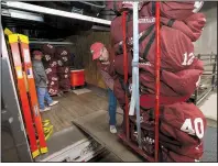  ?? NWA Democrat-Gazette/ANDY SHUPE ?? J.B. Hunt Transport employee (from right) Jerry Rico of Fayettevil­le pulls a stack of Arkansas Razorbacks football equipment into a truck Thursday with the help of Rodney Collins of Pensacola, Fla.
