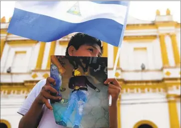  ?? Marvin Recinos AFP/ Getty I mages ?? A BOY HOLDS a photo of a person killed during violence in Nicaragua as he takes part in a protest demanding justice and the resignatio­n of long- ruling President Daniel Ortega in June 2018 in the city of Masaya.