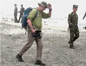  ?? — AP ?? Spirit of adventure: Shepherd walking past North Korean soldiers while leading an off-road hike on Mount Paektu.
