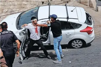  ??  ?? PALESTINIA­NS scuffle with a wounded Orthodox Jewish man who crashed his car near the Lions’ Gate, as clashes continued at the Temple Mount in the old city of Jerusalem, yesterday. | EPA