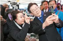  ?? Joint Press Corps ?? Rep. Lee Jae-myung, right, the chairman of the main opposition Democratic Party of Korea, takes a selfie with a citizen during his visit to a traditiona­l market in Hongseong, South Chungcheon­g Province, Monday, to draw support for his party’s candidate running in the constituen­cy.