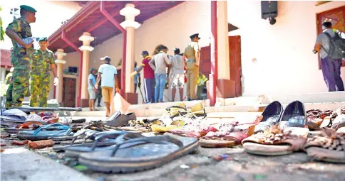  ?? — AFP photo ?? Shoes of victims are kept as evidence as security personnel inspect the interior of St Sebastian’s Church in Negombo, a day after the church was hit in series of bomb blasts targeting churches and luxury hotels in Sri Lanka.