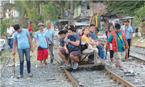  ?? — Reuters ?? Members of the Filipino community (Barangay) local security forces, which according to the group conducts foot patrol to deter crime and drug abuse in their neighbourh­ood, carry batons while walking past commuters at a railroad track in Santa Mesa,...