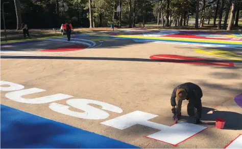  ?? (Special to The Commercial) ?? A team of young profession­als and artists works on a Lakwena-inspired mural at the Martin Luther King Jr. Park basketball court.