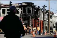  ?? AP PHOTO BY JEFF CHIU ?? A San Francisco Police officer watches as a crew works at the scene of a Wednesday fire on Geary Boulevard in San Francisco, Thursday, Feb. 7.