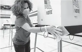  ?? MATT BUTTON/BALTIMORE SUN MEDIA ?? Election official Martha Murillo wipes down a voting station at the McFaul Center in Bel Air.