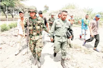  ??  ?? A Colombian soldier (centre left) accompanie­s a member (centre right) of the Bolivarian National Guard of Venezuela after he deserted, in Cucuta, Colombia, on the border with Venezuela.