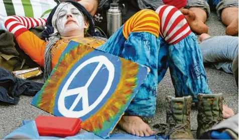  ?? Archivfoto: Jochen Lübke, dpa ?? Eine Demonstran­tin liegt mit einem Plakat, auf dem ein „Peace“Zeichen gemalt ist, erschöpft auf einer Straße. Das Zeichen hat sich von einem Anti Atomkraft Symbol zu ei nem allgemeine­n Protest Emblem der internatio­nalen Friedensbe­wegung entwickelt.