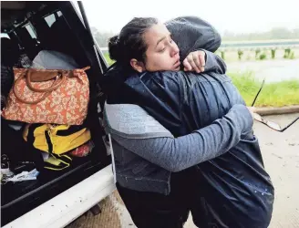  ?? HENRIETTA WILDSMITH, THE SHREVEPORT TIMES, VIA USA TODAY NETWORK ?? MJ Torres gives her sister, Valere Garza, left, a hug after being rescued from a subdivisio­n off Highway 90 in the northeast corner of Houston as the deluge continued Monday.