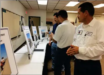  ?? Buy these photos at YumaSun.com PHOTOS BY MARA KNAUB/YUMA SUN ?? CESAR PONCE, WHO WORKS WITH the Yuma Street Department, views displays at an open house held Wednesday in honor of Public Works Week, while public works managers Martin Agundez and Joseph Lopez discuss other photos in the background.