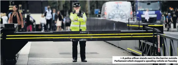  ??  ?? &gt; A police officer stands next to the barrier outside Parliament which stopped a speeding vehicle on Tuesday