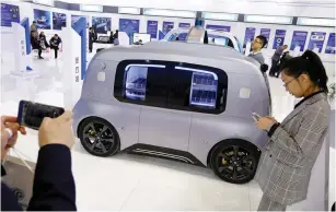  ?? (Thomas Peter/Reuters) ?? A VISITOR takes a picture of a Neolix self-driving vehicle at the IEEV New Energy Vehicles Exhibition last year in Beijing.