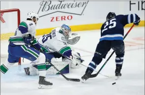  ?? The Canadian Press ?? Vancouver Canucks goaltender Thatcher Demko pokes the puck away from Winnipeg Jets’ Paul Stastny as Jordie Benn defends in Winnipeg on Saturday. Brock Boeser scored two goals, rookie Nils Hoglander and Zack MacEwen also scored in a 4-1 victory.