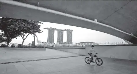  ?? BloomBerg News ?? The Marina Bay Sands hotel is seen at this photo of a bicyclist in a park in Singapore. Citigroup Inc. plans to partner with UBS AG for an electronic currency trading and pricing platform in the Lion City.