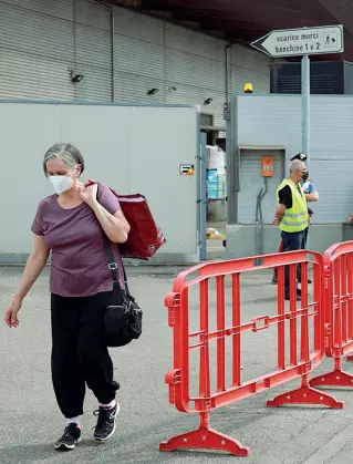  ??  ?? Testa bassa Una dipendente esce dal centro commercial­e con i propri effetti personali (Cambi/Sestini)