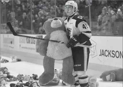  ?? PHOTOS BY BARRY GRAY, THE HAMILTON SPECTATOR ?? Bulldogs forward Will Bitten picks up a giant teddy bear as he helps clean up the ice during the annual toy toss game Saturday, when fans threw stuffed toys onto the ice following the Dogs’ first goal of the game. The toys are donated to charity for...