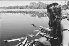  ?? — Photo by The Canadian Press ?? Little Buffalo band member Melina Laboucan-Massimo recently scoops up what appears to oil from the pond shoreline near the site of a 4.5 million-litre Plains Midstream pipeline leak detected April 29, 2011.