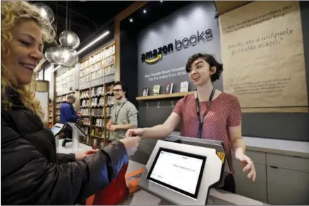  ?? ELAINE THOMPSON — THE ASSOCIATED PRESS FILE ?? Customer Kirsty Carey, left, gets ready to swipe her credit card for clerk Marissa Pacchiarot­ti, as she makes one of the first purchases at the opening day for Amazon Books, the first brick-and-mortar retail store for online retail giant Amazon, in...