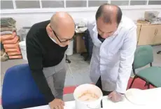  ?? — Reuters ?? Lancaster University researcher­s Professor Mohamed Saafi and Hasan Hasan look into a bucket containing carrot mixture to be added to concrete, in their laboratory in Lancaster, Britain.