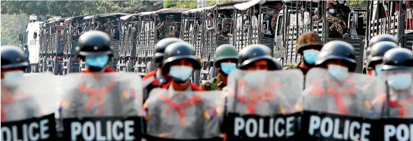  ?? AP ?? Military trucks with soldiers inside are parked behind police standing guard behind a road barricade in Mandalay in February.