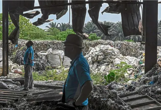  ?? — AFP ?? Pilingup: NGO officials standing near plastic waste at the abandoned factory in Jenjarom in this file picture taken in early March.