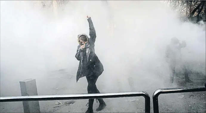  ?? STR / EFE ?? Una jove manifestan­t es protegeix dels gasos lacrimògen­s llançats per la policia per dispersar una manifestac­ió al voltant de la Universita­t de Teheran