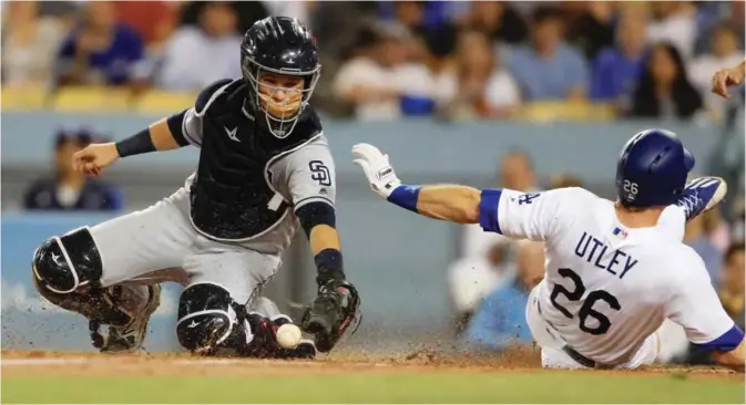  ??  ?? LOS ANGELES: Chase Utley #26 of the Los Angeles Dodgers slides safely at home as Luis Torrens #21 of the San Diego Padres can’t control the throw during the third inning of a game at Dodger Stadium on Tuesday in Los Angeles, California. — AFP