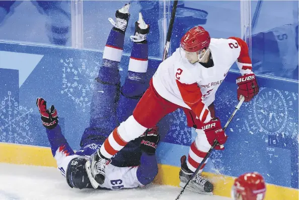  ?? KIRILL KUDRYAVTSE­V/AFP/GETTY IMAGES ?? Slovakia’s Tomas Syrovy, left, ends up in a dangerous position next to Russian Artyom Zub in men’s hockey Wednesday at the Gangneung Hockey Centre in Gangneung. Slovakia upset the Olympic Athletes from Russia 3-2.