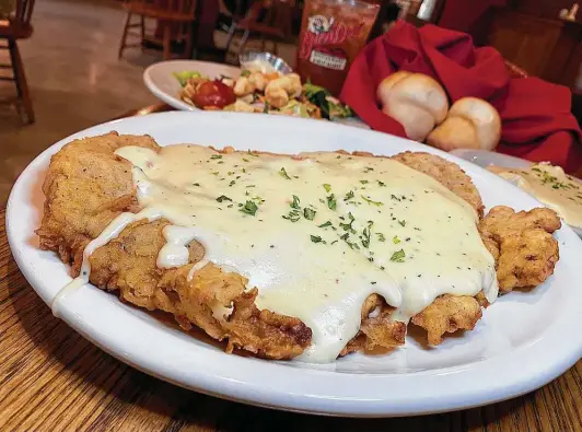  ?? Photos by Mike Sutter / Staff ?? Chicken-fried steak is made with rib-eye steak and served with cream gravy, mashed potatoes, salad and fresh rolls at The Barn Door Restaurant & Meat Market.