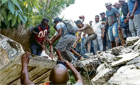  ?? DELOT JEAN / AP ?? Un grup de persones rescata el cos d’una de las víctimes d’un edifici esfondrat a Les Cayes