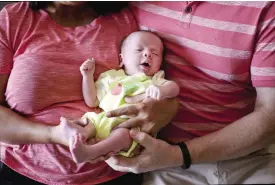  ??  ?? ANAND: A couple from Britain hold their baby, born on Oct 17 by a surrogate, in Anand, India. — AP