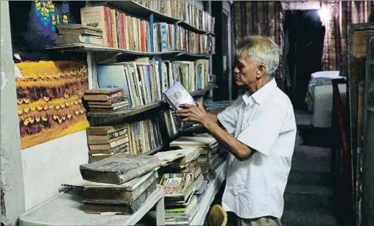  ?? ISMAEL ARANA ?? La lectura como regalo Hernando Guanlao, de 66 años, coloca un libro en una estantería de su particular casa librería; debajo, cartel en la fachada