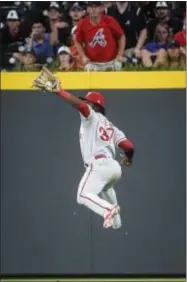  ?? JOHN AMIS — THE ASSOCIATED PRESS ?? Phillies center fielder Odubel Herrera leaps to catch a line drive hit by the Braves’ Brandon Phillips in the eighth inning Tuesday in Atlanta.