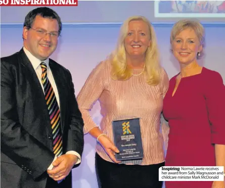  ??  ?? Inspiring Norma Lawrie receives her award from Sally Magnusson and childcare minister Mark McDonald