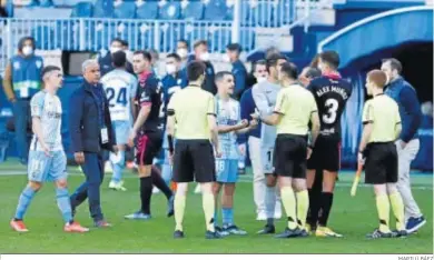  ?? MARILÚ BÁEZ ?? Los jugadores del Málaga y Sergio Pellicer reclaman al colegiado explicacio­nes tras el partido ante el Tenerife.