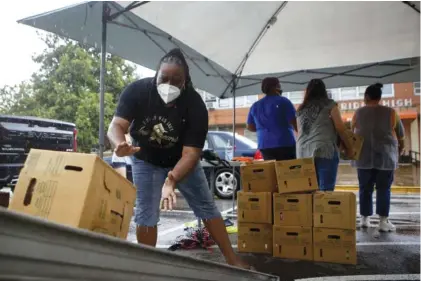  ?? STAFF PHOTO BY C.B. SCHMELTER ?? We Over Me co-founder Lakweshia Ewing, left, helps unload and stack produce boxes at We Over Me’s “Pop-Up Produce Stand” at East Ridge High School on Thursday in East Ridge. We Over Me provided boxes of fresh produce free of charge.