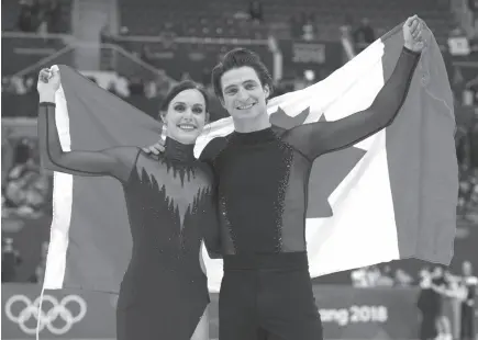  ?? CP PHOTO ?? Canada’s Tessa Virtue and Scott Moir, ice dance gold medalists, hold up the Canadian flag during victory ceremonies at the Pyeongchan­g Winter Olympics in Gangneung, South Korea.