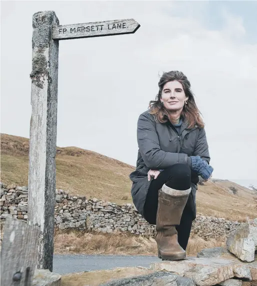  ?? PICTURE: TIM SMITH. ?? SEMERWATER-BOUND: Yorkshire Shepherdes­s Amanda Owen pauses by a drystone wall next to the Marsett Lane footpath sign.