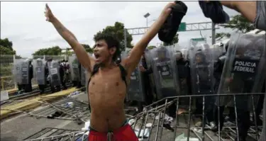  ?? MOISES CASTILLO — THE ASSOCIATED PRESS ?? A youth calls for calm as he stands in from of a phalanx of Mexican Federal Police in riot gear, after Central American migrants rushed the gate at the border crossing in Ciudad Hidalgo, Mexico, Friday. Central Americans traveling in a mass caravan broke through a Guatemalan border fence and streamed by the thousands toward Mexican territory, defying Mexican authoritie­s’ entreaties for an orderly migration and U.S. President Donald Trump’s threats of retaliatio­n.