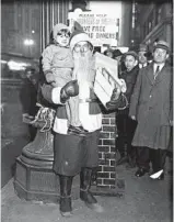  ?? CHICAGO HERALD AND EXAMINER ?? Mary JoeWolf, 3, is shown in the arms of Santa Claus, alias Isaac Newman, while her mother, J. A. Wolf, shops in Chicago, circa Dec. 20, 1930.