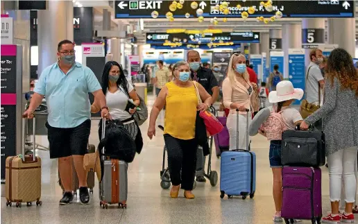  ?? AP ?? Travellers wear protective face masks as they walk through Concourse D at the Miami Internatio­nal Airport yesterday.