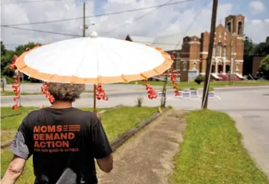  ?? STAFF PHOTO BY DOUG STRICKLAND ?? Linda Rudder carries a parasol during the Wear Orange event near Glass Street on Saturday. Organizers with the group Moms Demand Action brought community members together to remember victims of gun violence in solidarity with a national movement.